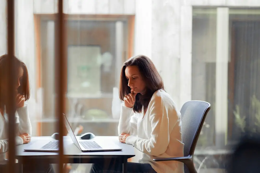 a woman sitting at a table with a laptop computer