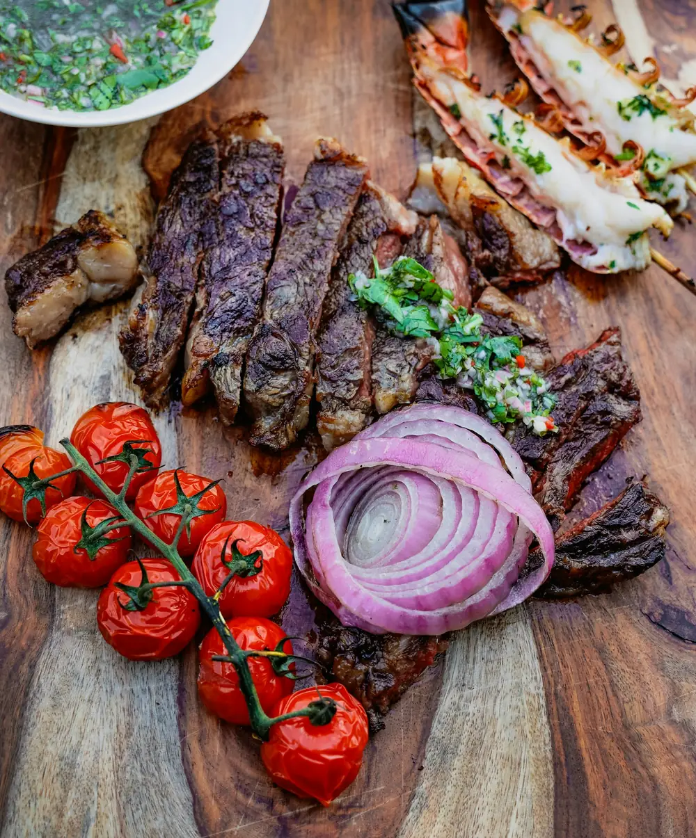 a wooden cutting board topped with meat and veggies